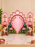 A decorative pink and gold Hindu festival backdrop set featuring a central pink lotus arch with peacocks and elephants, flanked by two matching side panels with hanging lanterns and lotus flowers.